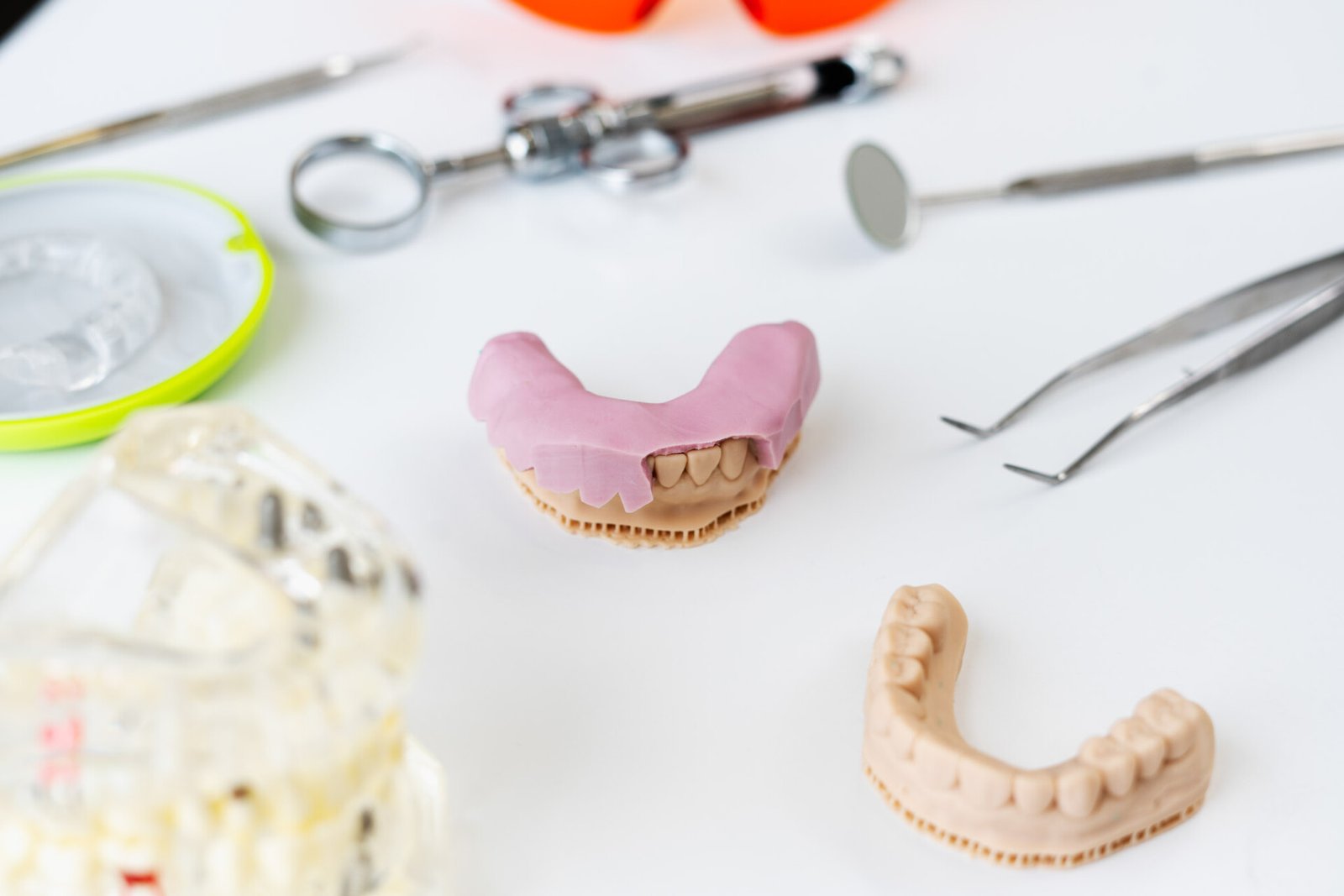 Porcelain dental cast, mirror and iron forceps laying at the white table. Capitol Dental Laboratory